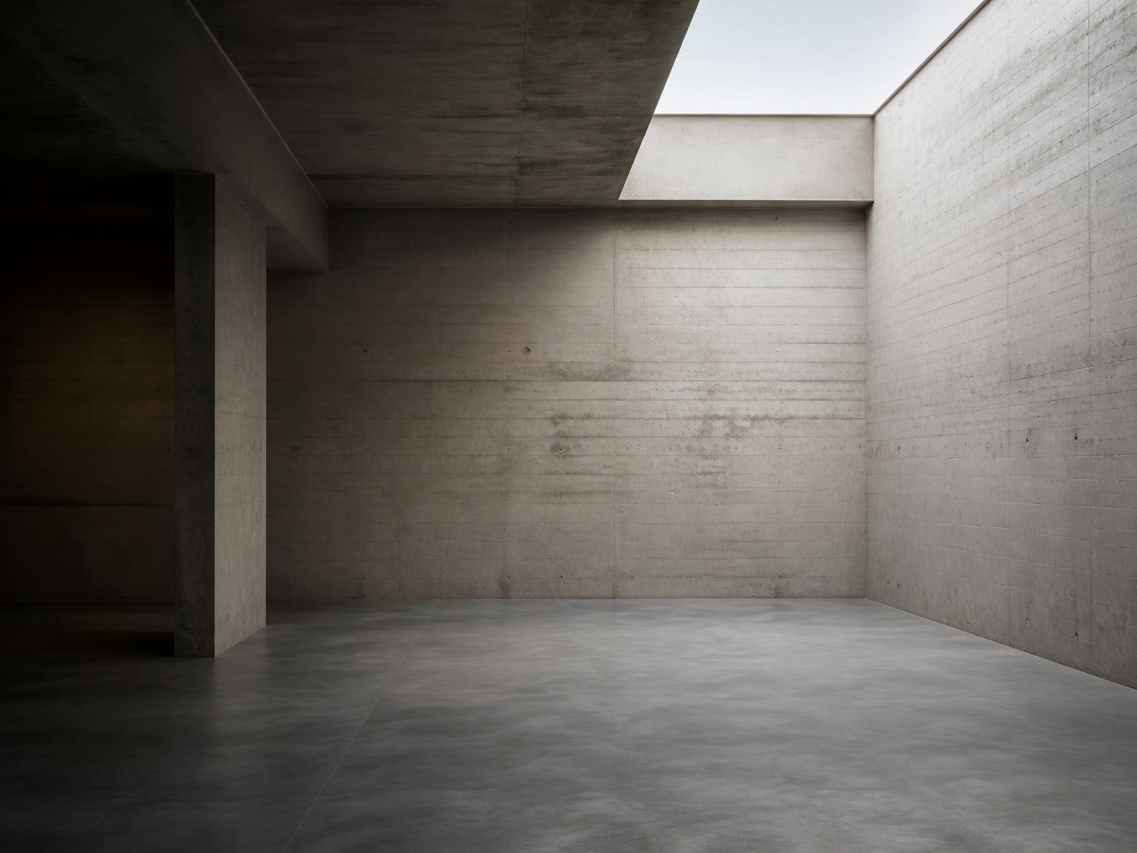 Empty concrete space lit by a skylight